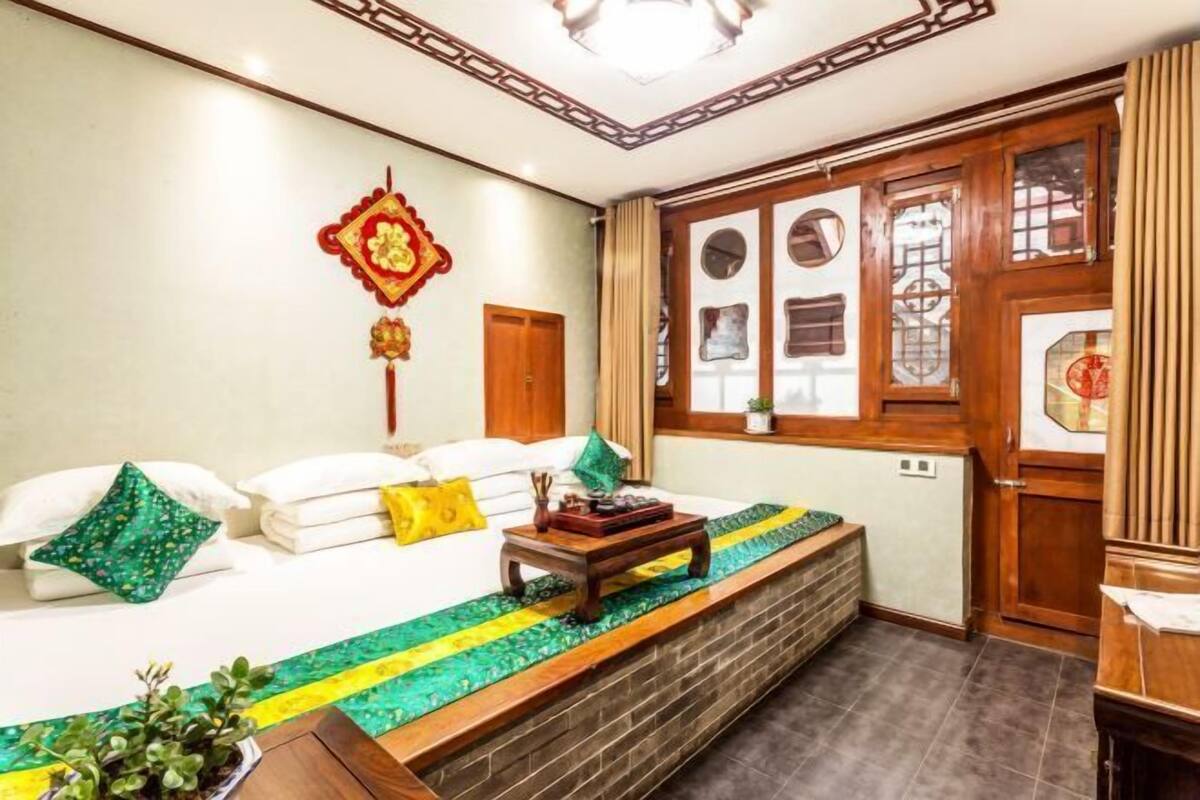 Une chambre d’hôtel comprenant un lit, un banc en bois, un élément de décoration murale et une fenêtre au design traditionnel.