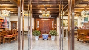 Eine geräumige Lobby mit einem Holzbüro, Topfpflanzen und einem großen, blau-weißen Keramikonstück.