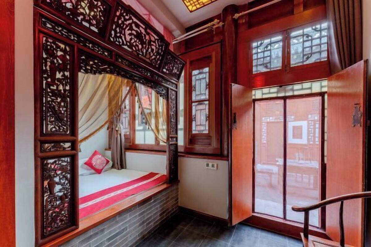 Une chambre traditionnelle avec un lit en bois, une fenêtre donnant sur un beau paysage et une porte.