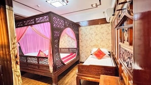 Ein traditionell eingerichtetes Zimmer mit einem Himmelbett, einem Einzelbett und einer hölzernen Sitzbank.