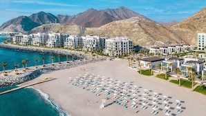 A beachfront hotel with multiple buildings, a sandy beach, and a rocky coastline. - Capital Stay | 2 Bed Apt |  The Address Fujairah (Fujairah)