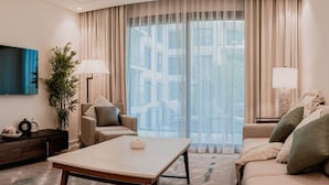 A modern living room with a large window, a sofa, a coffee table, and a lamp. - Capital Stay | 2 Bed Apt |  The Address Fujairah (Fujairah)