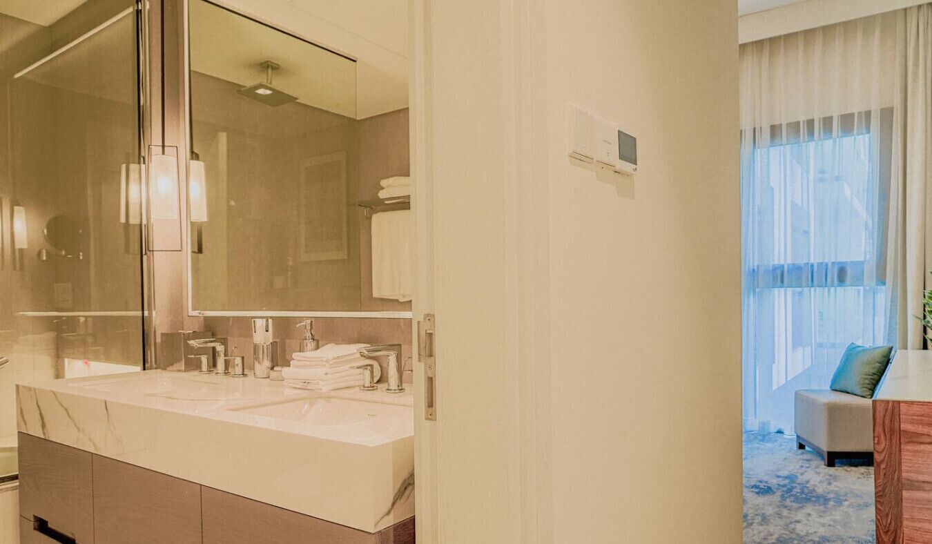 A modern bathroom with a large mirror, dual sinks, and a towel rack.