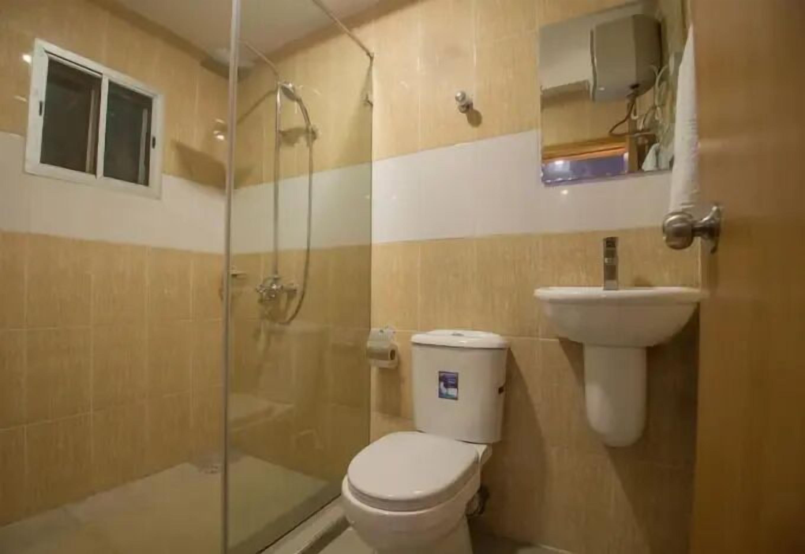 Un baño con ducha de vidrio, inodoro y lavabo.