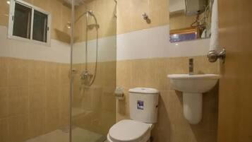 Un baño con ducha de vidrio, inodoro y lavabo.