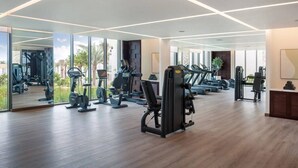 A modern gym with various exercise equipment, large windows, and a clean, spacious layout.