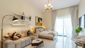 A modern hotel room with a sofa, a bed, a dining table, and a TV. - Capital Stay - Cozy Studio in Liwan Dubai (Dubai)