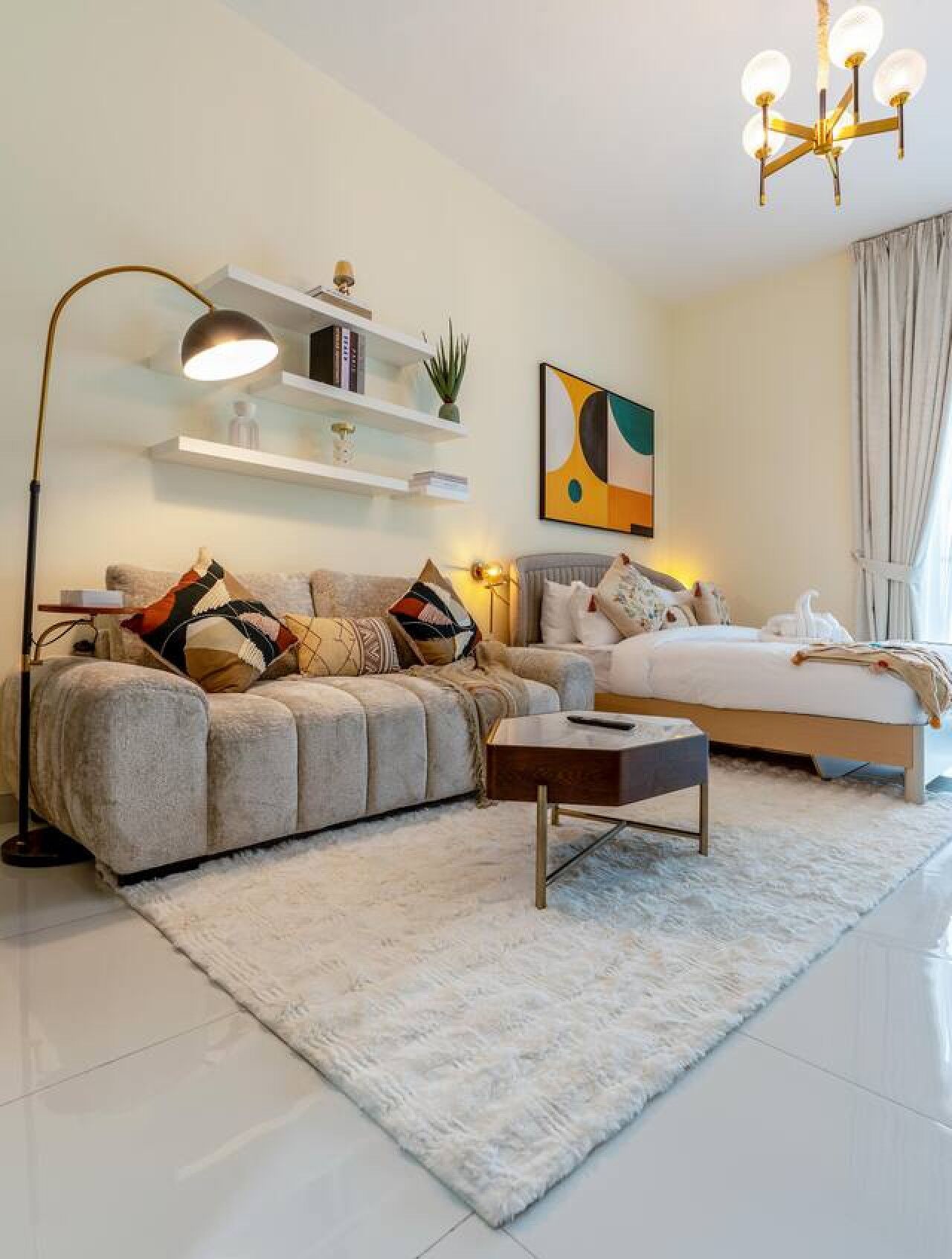 A modern bedroom with a sofa, a bed, a nightstand, and a floor lamp.