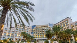 Un hôtel à plusieurs étages, doté de palmiers et d’un bâtiment moderne avec des balcons.