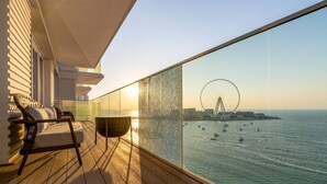 Een balkon met uitzicht op de zee en een reuzenrad in de verte.