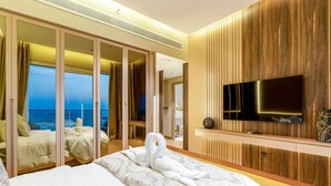 Een hotelkamer met een groot bed, een televisie en uitzicht op zee.