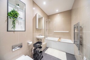 Une salle de bain moderne équipée d’une baignoire, d’un lavabo, d’un miroir et d’un porte-serviettes.