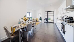 Eine moderne Küche mit eingebautem Herd, ein Essbereich mit Tisch für Zwei und eine Schiebetür zu einem Balkon.