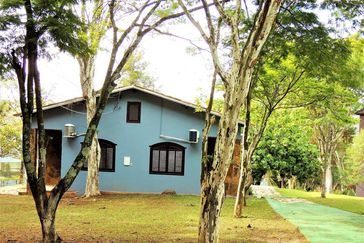 A house with a blue exterior, surrounded by trees and a grassy area.