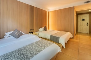 Habitación de hotel con dos camas, paneles de madera, una puerta blanca y piso de baldosas.