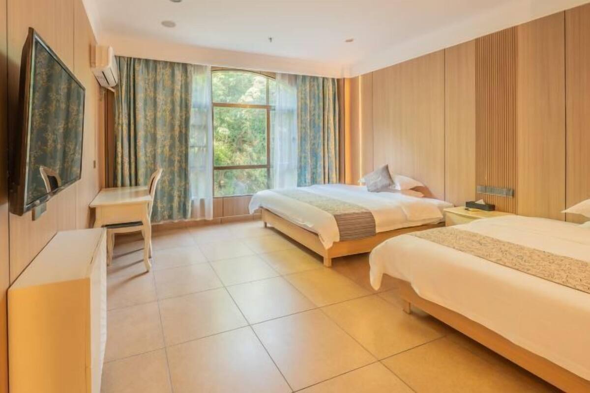 A hotel room with a bed, a desk, and a TV.