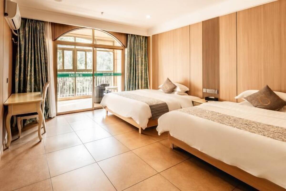 A hotel room with two beds, a desk, and a window with curtains.