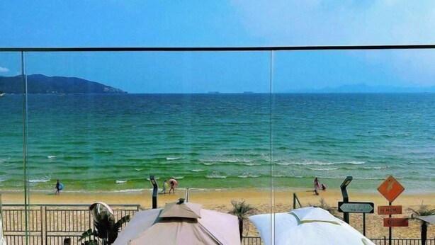 A beach view with umbrellas and a sign indicating a nearby location. - L.V.BAY (Shenzhen)