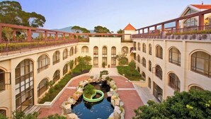 A courtyard with a central water feature, surrounded by buildings with arched windows and a red bridge. - L.V.BAY (Shenzhen)