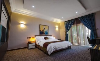 Quarto de hotel com cama, abajures, um quadro na parede e vista para o exterior pela janela.