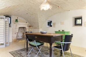 A rustic dining area with a stone fireplace, a wooden table, and black chairs.