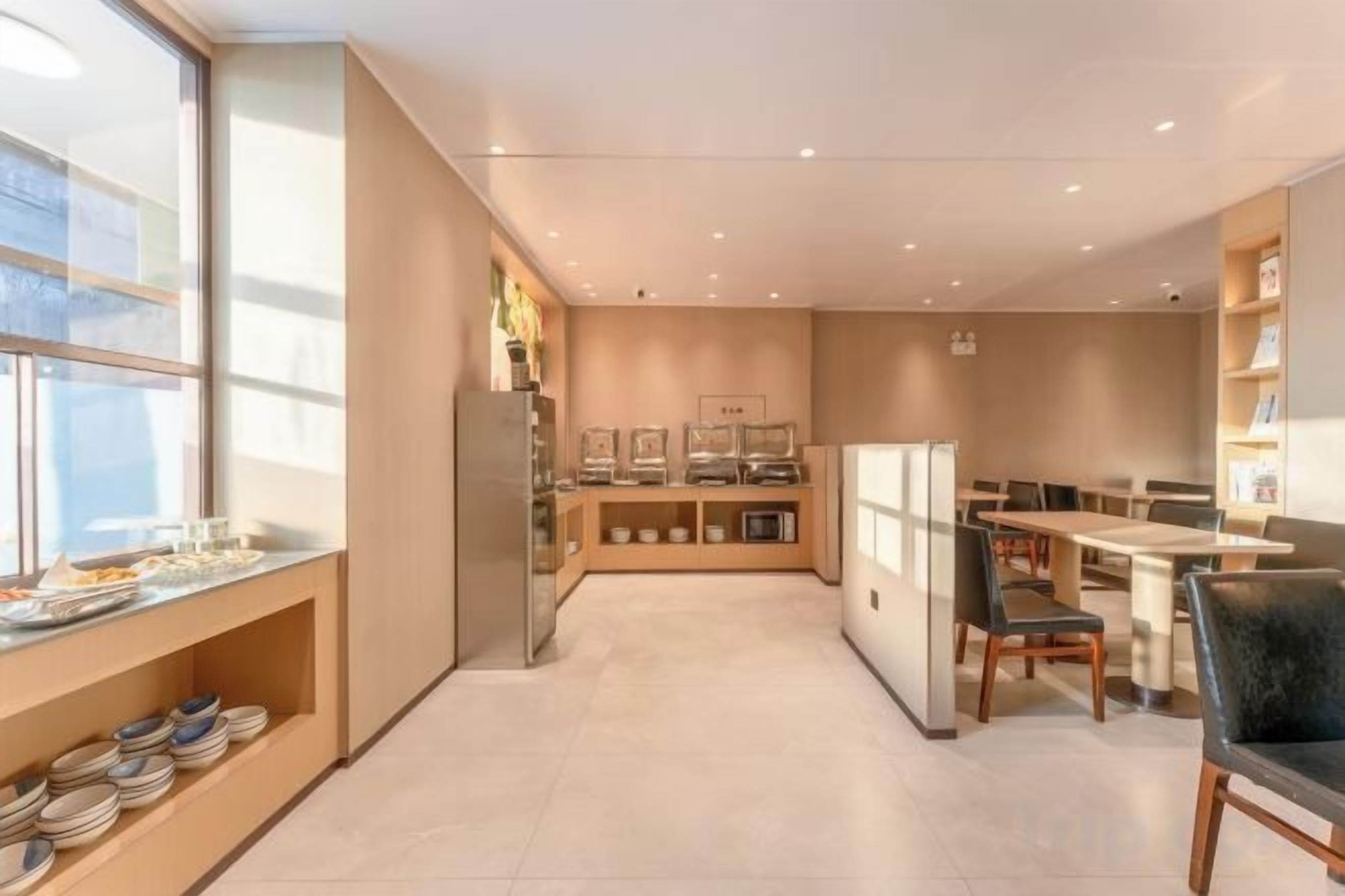 A modern kitchen with a refrigerator, a dining area with chairs and tables, and a window providing natural light.