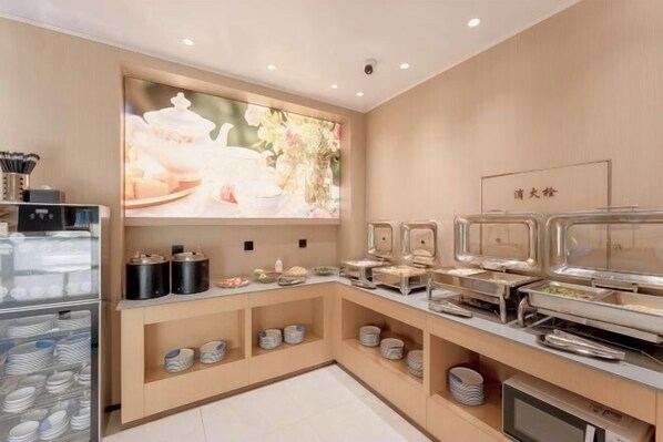 A buffet area with various food stations, a refrigerator with dishes, and a wall-mounted screen displaying floral imagery. - Dayang Hotel (Harbin)