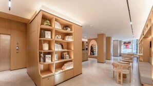 Ein modernes Interieur mit einem großen Bücherregal aus Holz, einer Sitzecke mit Holzstühlen und einem Fliesenboden.