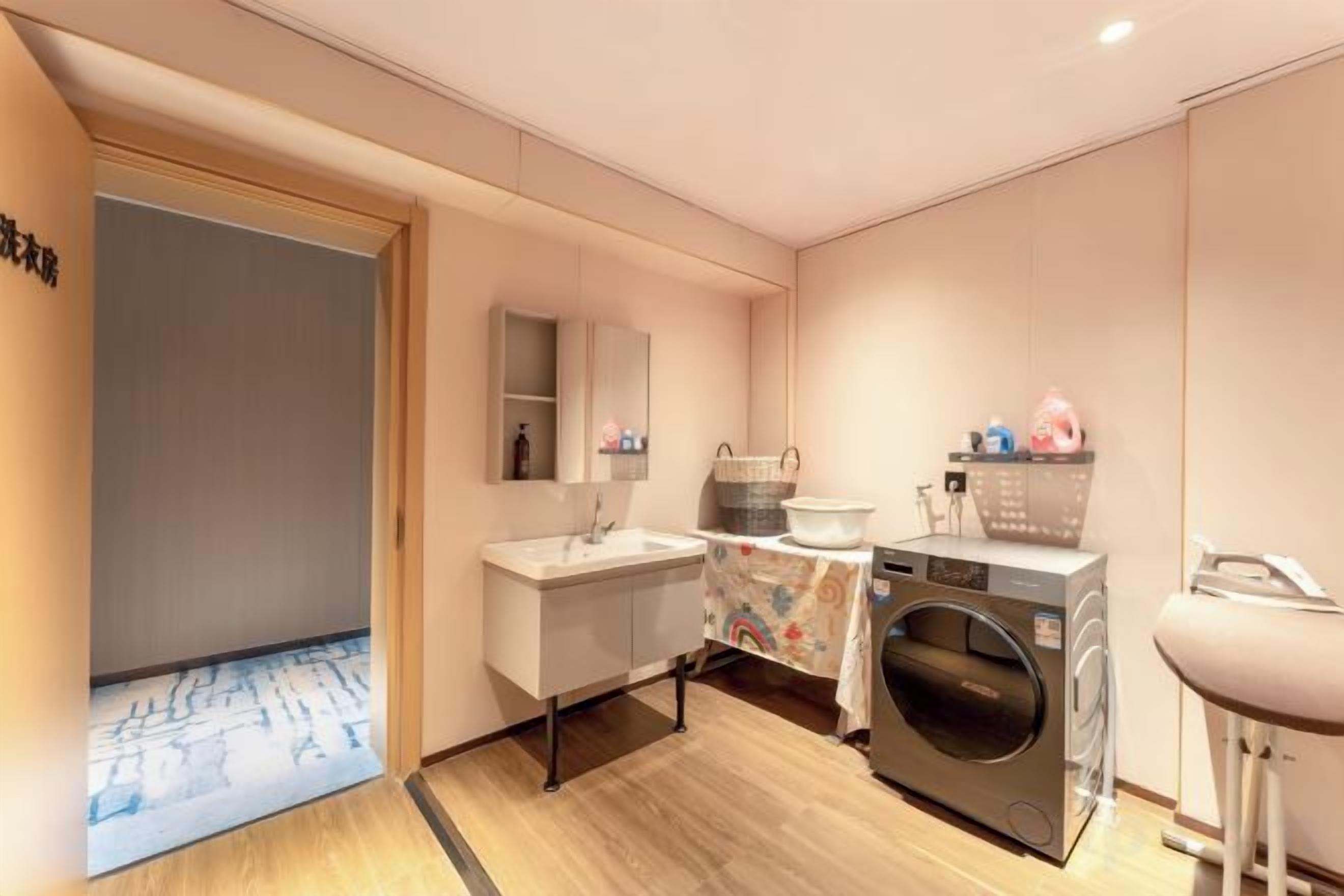 A modern bathroom with a sink, mirror, and washing machine.