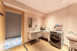 A modern bathroom with a sink, mirror, and washing machine. - Dayang Hotel (Harbin)