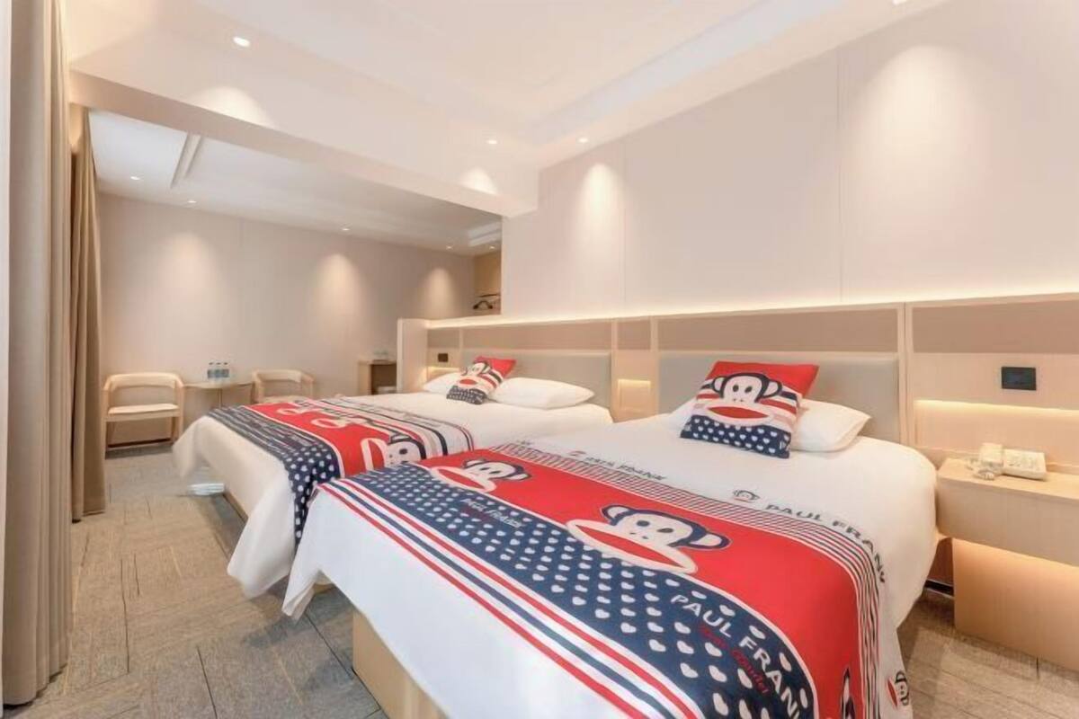 Ein Hotelzimmer mit zwei Betten, einem Schreibtisch, einem Stuhl und einem Nachttisch.
