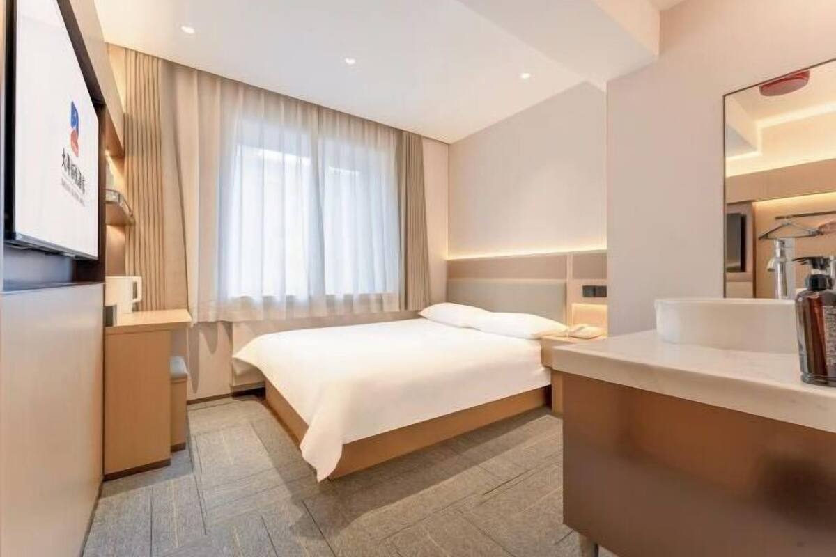 Ein Hotelzimmer mit Bett, Nachttisch und einem großen Spiegel.