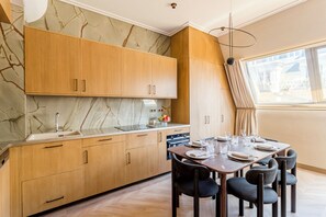 A modern kitchen with wooden cabinets, a marble backsplash, and a dining area with a table set for four.