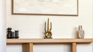 Un intérieur moderne agrémenté d’une console en bois, d’un tableau abstrait encadré et d’un vase décoratif.