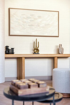 A modern interior with a wooden console table, a framed abstract painting, and a decorative vase.