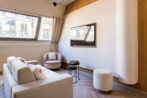 A modern living room with a sofa, armchair, ottoman, and a small side table.