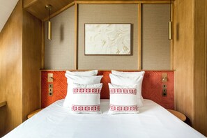A hotel room with a wooden headboard, a framed artwork above the bed, and a red accent wall.