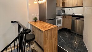A modern kitchen with a wooden island, stainless steel appliances, and a black marble backsplash. - Apartment in the heart of the Latin Quarter - Perfect for discovering Paris! (Paris)