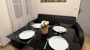 Une table à manger dressée avec de l’assiette blanche, des couverts et un vase de fleurs.