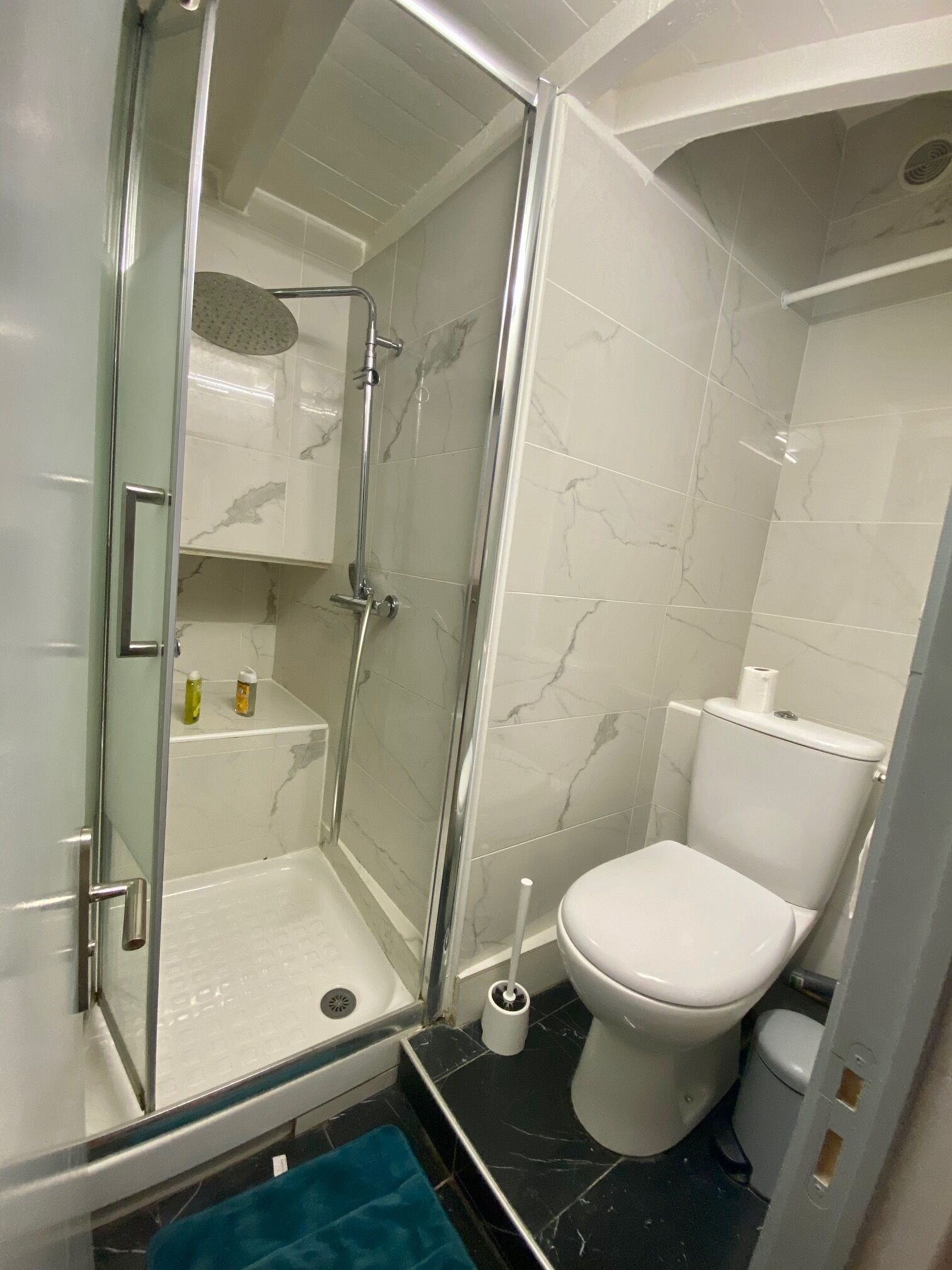 A bathroom with a glass-enclosed shower, a toilet, and a sink.