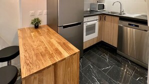 Une cuisine moderne dotée d’un îlot central en bois, d’appareils électroménagers en acier inoxydable et d’un sol en marbre noir.