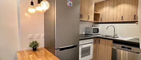 A modern kitchen with a wooden island, stainless steel appliances, and a black marble floor.