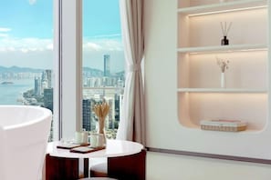 Enjoy a panoramic city view from the comfort of this stylish room, featuring a round table for relaxation and a shelving unit with soft lighting.