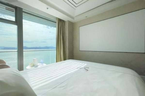 Een hotelkamer met een groot bed, uitzicht op zee en een whiteboard aan de muur.
