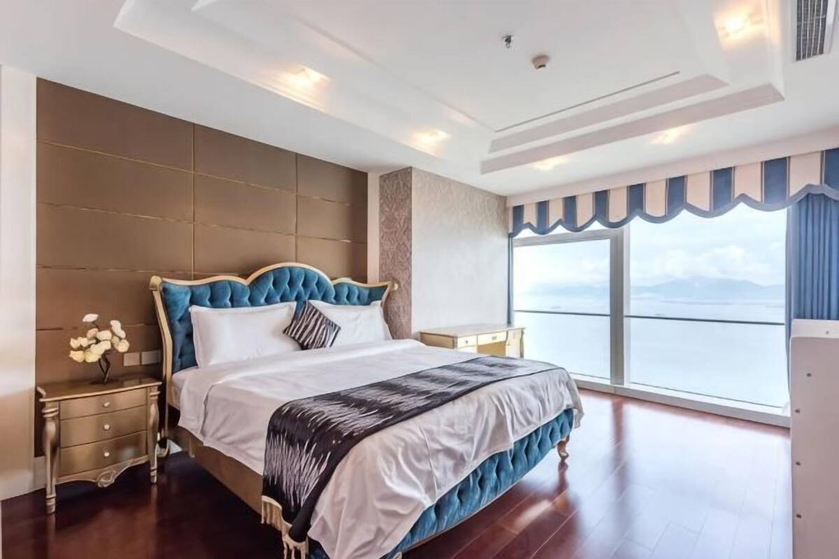 Un dormitorio con una cama grande, una mesita de noche, un aparador y vistas al mar.