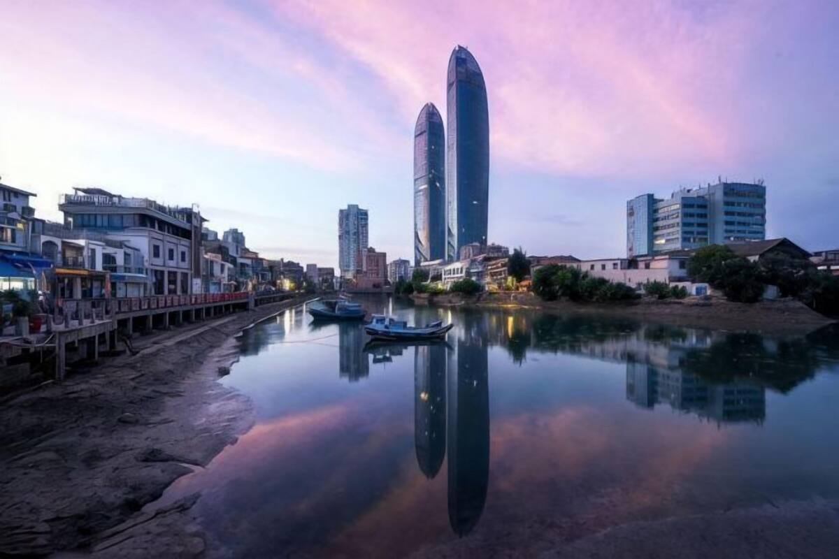 Un paisaje urbano frente al río, con edificios modernos, un río tranquilo y un muelle.