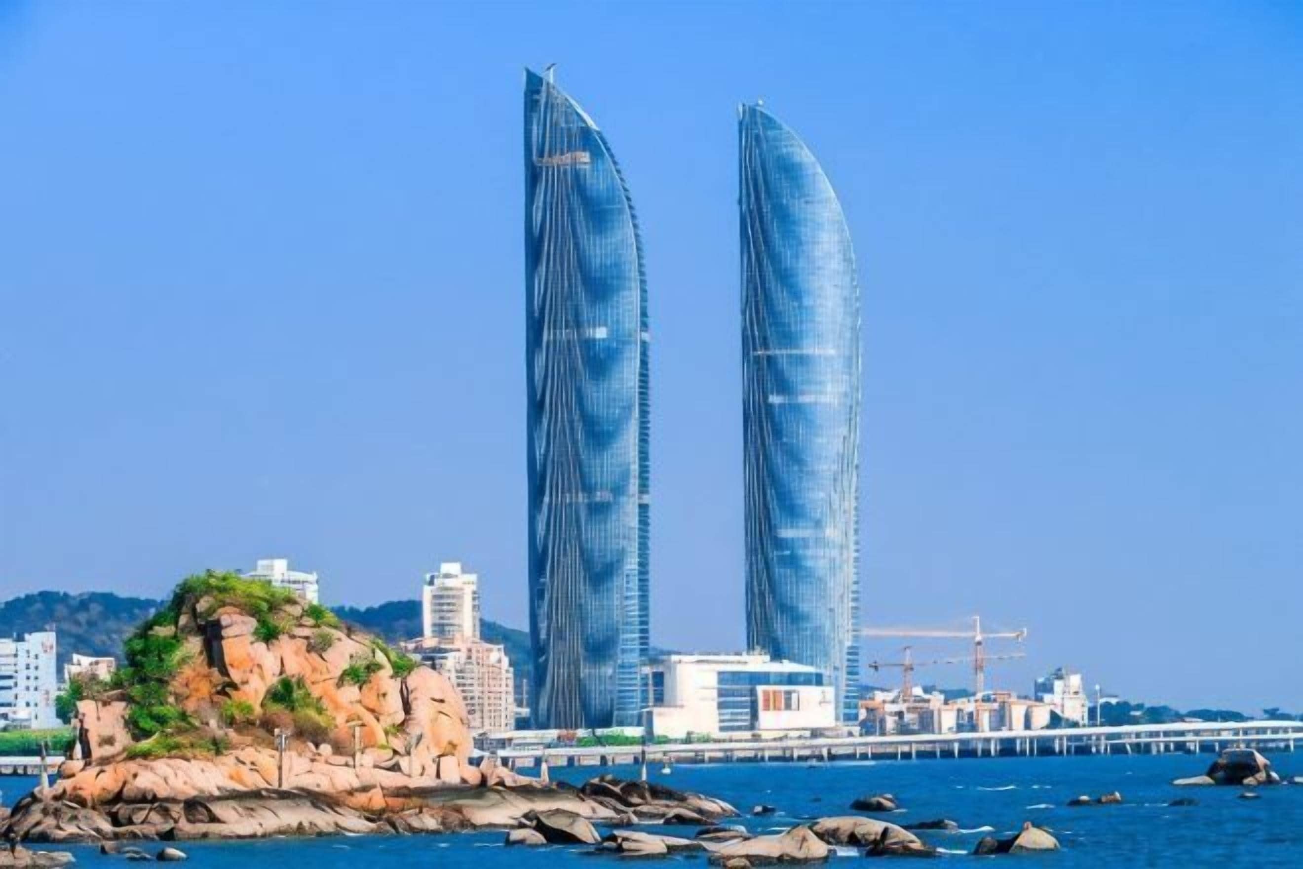 Two tall buildings with a clear blue sky in the background.