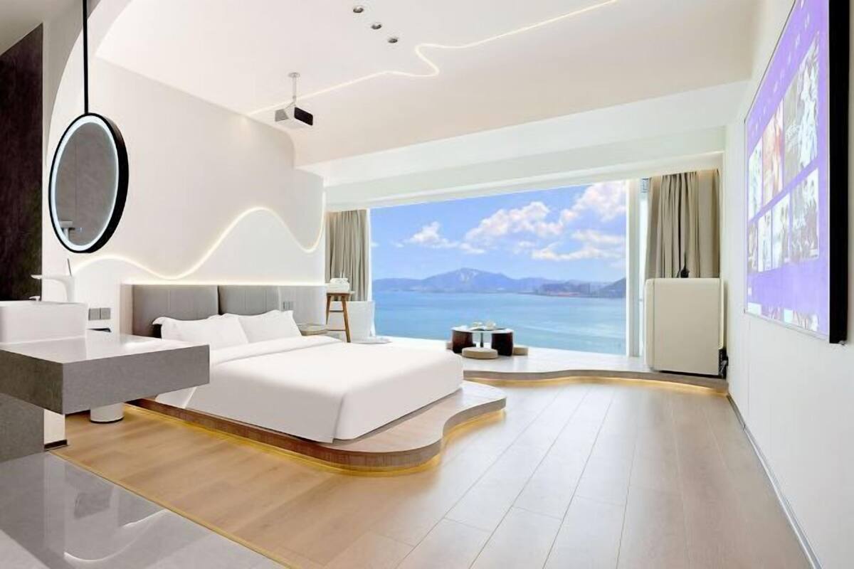 Habitación de hotel moderna con una cama grande, tocador, escritorio y vistas al mar.