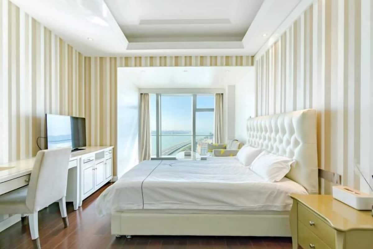 Habitación de hotel con cama, escritorio, silla, televisión y vistas a la ciudad.