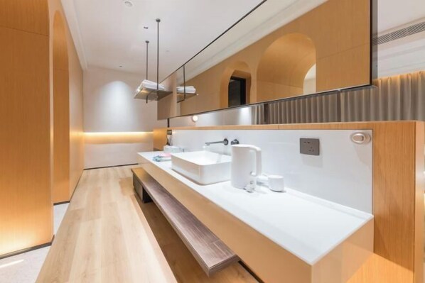 Un baño moderno con un espejo grande, un lavabo blanco y un banco.